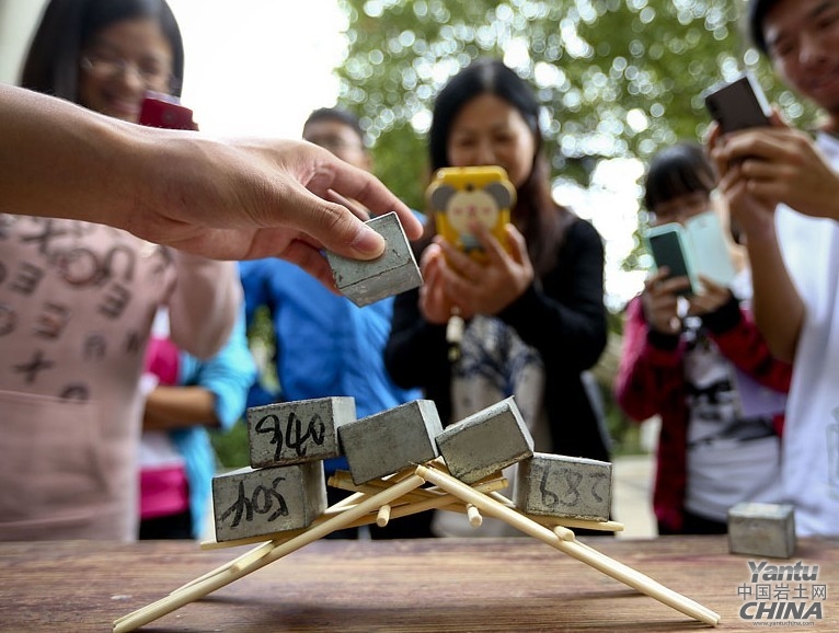 图为学生用18根一次性筷子搭建的简易桥梁承载着近十斤的铅块依然不倒